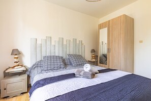 Un lit bien fait, avec une literie à motifs, une table de chevet avec une lampe et une armoire en bois.