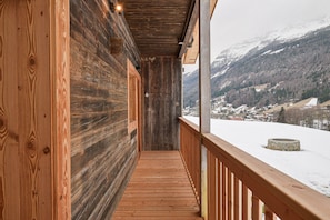Een houten hut met balkon, met uitzicht op een besneeuwd berglandschap.