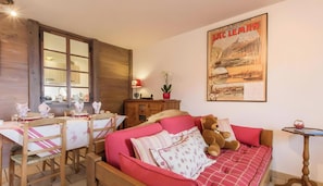 Une pièce chaleureuse avec une table à manger en bois, des chaises, un canapé et une affiche accrochée au mur.