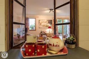 Een kamer met uitzicht, een tafel met mokken en een theepot, en een schilderij van ijsberen aan de muur.
