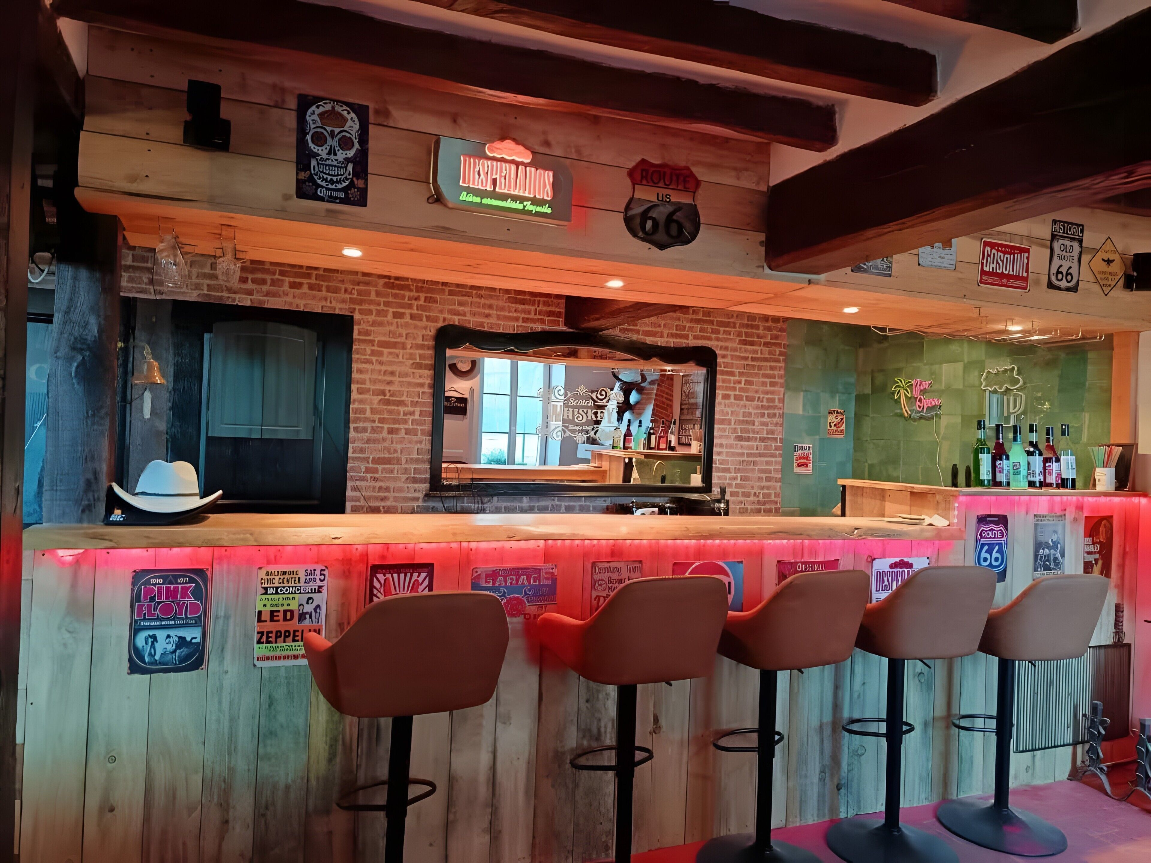 Zona de bar con un letrero de neón, un cartel de la Ruta 66 y un espejo que refleja el interior.