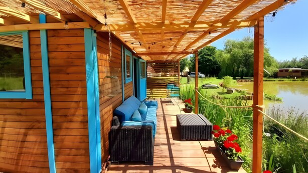 Eine Holzhütte mit überdachter Veranda, einem blauen Sofa und einem kleinen Tisch.