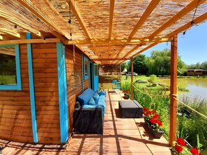 Eine Holzhütte mit überdachter Veranda, einem blauen Sofa und einem kleinen Tisch.