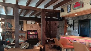 Eine rustikale Bar mit Holzbalken, einer Ziegelwand und einer Theke mit Hockern.