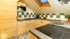 Une cuisine avec des meubles en bois, un four à micro-ondes, une cuisinière à gaz et un dosseret à carreaux.