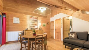 Un intérieur en bois comprenant une table à manger, des chaises, un canapé et un luminaire suspendu.