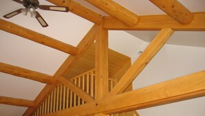 Eine Holzbalkenkonstruktion mit Deckenventilator, Holzbalken und einer Treppe.