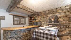 Una cocina rústica con paredes de piedra, un mostrador de madera y un mantel a cuadros.