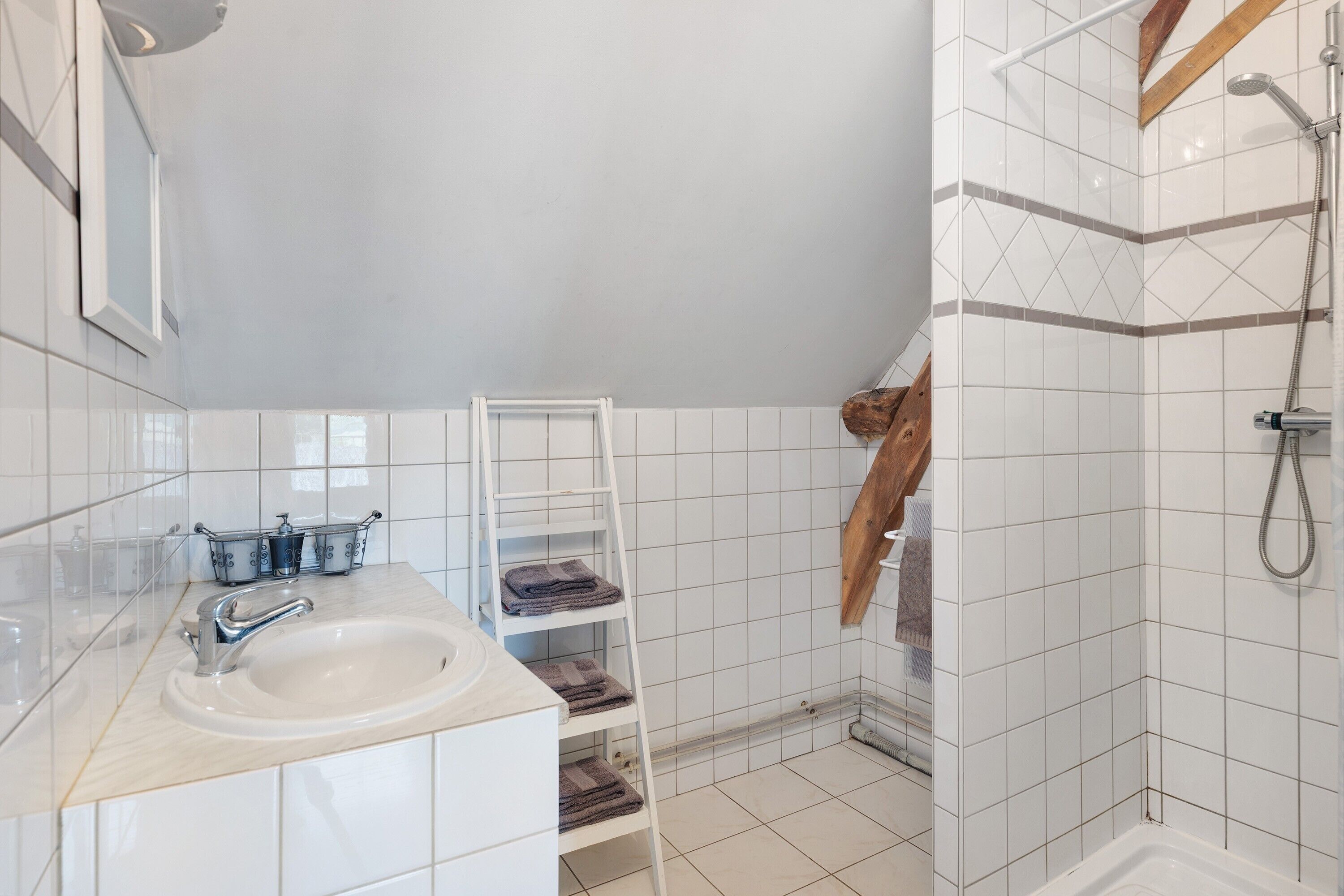 Une salle de bain avec un lavabo, une douche et une étagère en bois.