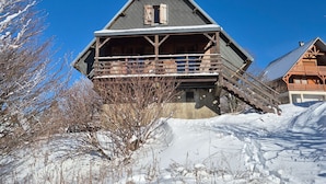 Una cabaña de madera con balcón, rodeada de nieve.