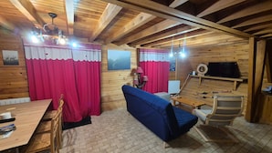 Un interior de madera con una mesa de comedor, un sofá azul y un televisor.