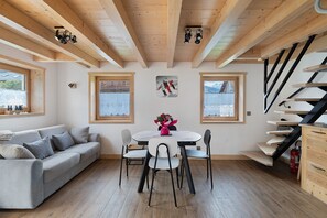 A modern interior with a wooden ceiling, a sofa, a dining table with chairs, and a staircase.