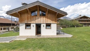 A wooden chalet with a sloped roof, a small porch, and a door leading to the interior.