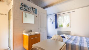 Ein Zimmer mit Bett, Schreibtisch, Stuhl, Waschbecken und Spiegel.
