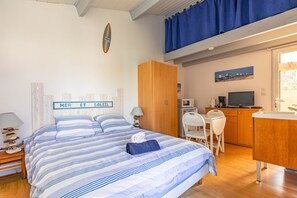 Une chambre comprenant un lit, un bureau, une chaise, une télévision et un coin cuisine.