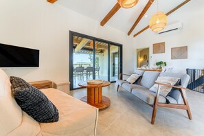 Een moderne woonkamer met een bank, een salontafel en een aan de muur bevestigde televisie.