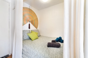 Ein Schlafzimmer mit einem Bett, Kissen, einem Ventilator und einem zusammengerollten Handtuch.