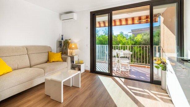 Een moderne woonkamer met een bank, een kleine tafel en een balkon met een tafel en stoelen.