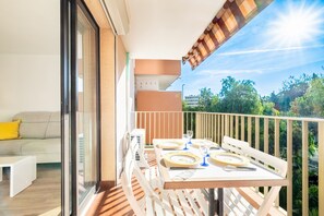 Un balcon avec une table dressée pour le repas, un canapé et une porte-fenêtre coulissante.
