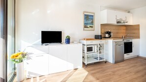 Een moderne keuken met een flatscreen televisie, een magnetron, een koffiezetapparaat en een houten spatwand.