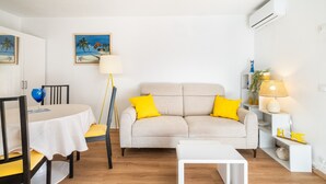 Een woonkamer met een bank, een eettafel en een lamp.