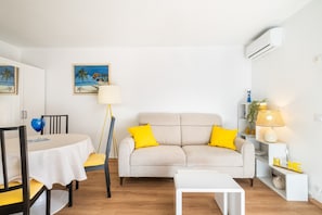 Ein Wohnzimmer mit einer Couch, einem Esstisch und einer Lampe.