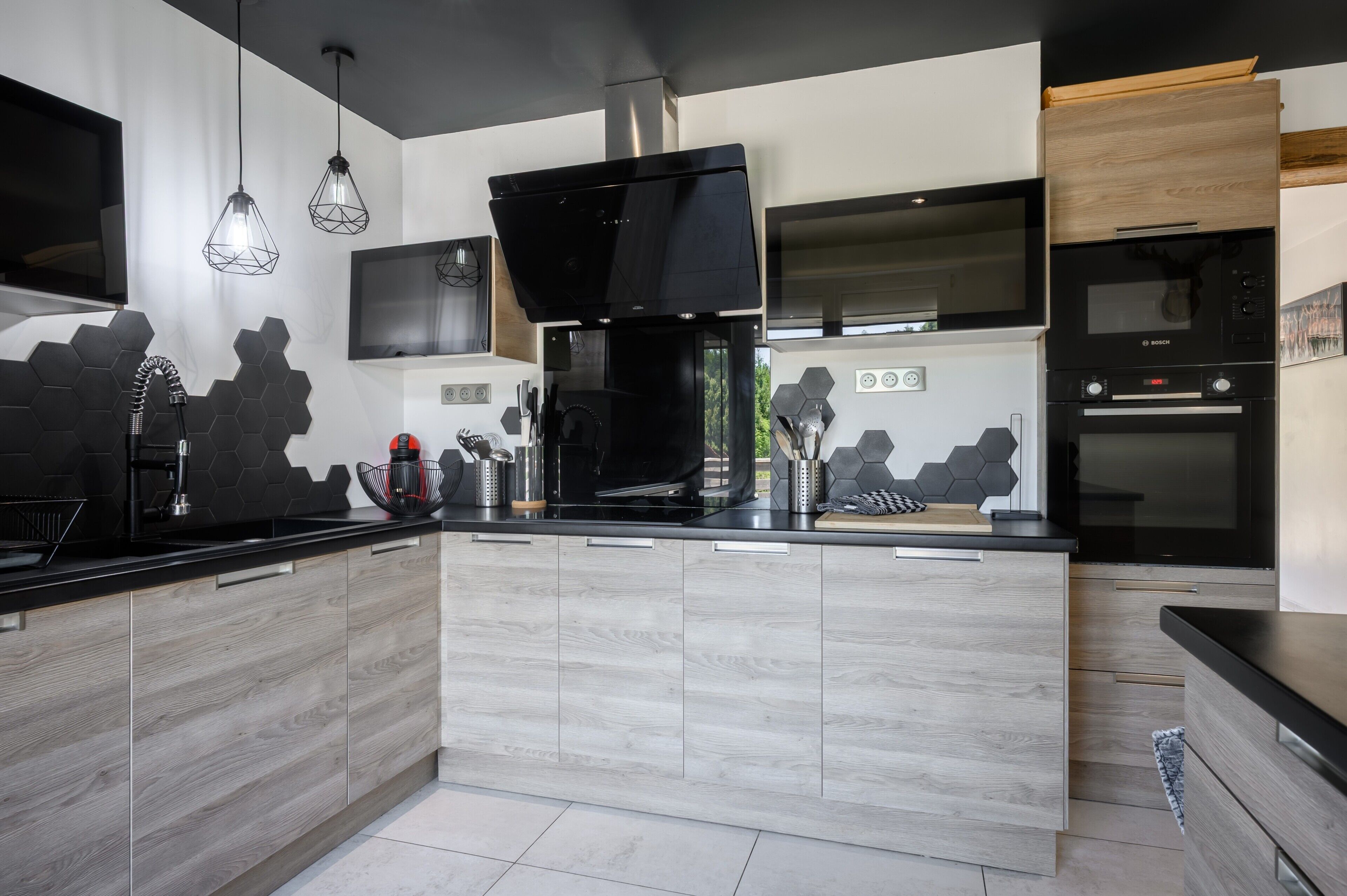 Una cocina moderna con una isla central, electrodomésticos negros y un salpicadero de madera.