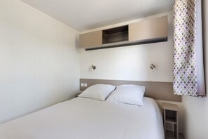 A single bed with a headboard, a bedside table, and a small shelf. - Bungalow "Les Lodges Des Pins" – Cozy Retreat in Lège-Cap-Ferret (Lège-Cap-Ferret)