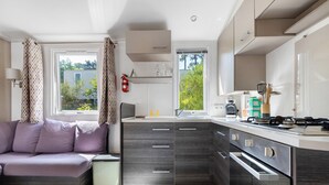 Une cuisine moderne dotée d’appareils électroménagers intégrés, un coin repas avec un canapé et une fenêtre avec des rideaux.