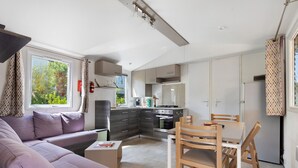 Une cuisine moderne dotée d’appareils électroménagers intégrés, un coin repas avec des chaises en bois, un canapé et une petite table.