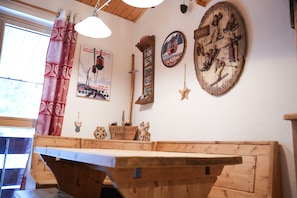 Un banc en bois avec une table devant, une horloge murale, une affiche et une enseigne en bois avec du texte.
