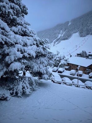 A snow-covered mountain with a ski lift, a wooden building, and parked cars. - Cozy Nest La Norma Les Campanules (Villarodin-Bourget)