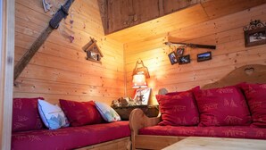 A cozy cabin interior with wooden walls, a wooden bed, a bench, and a table.