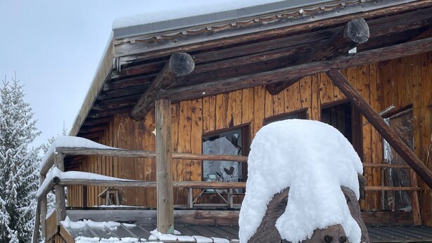 A wooden building with a rustic exterior, a wooden sculpture of a horse's head, and a sign indicating a restaurant.