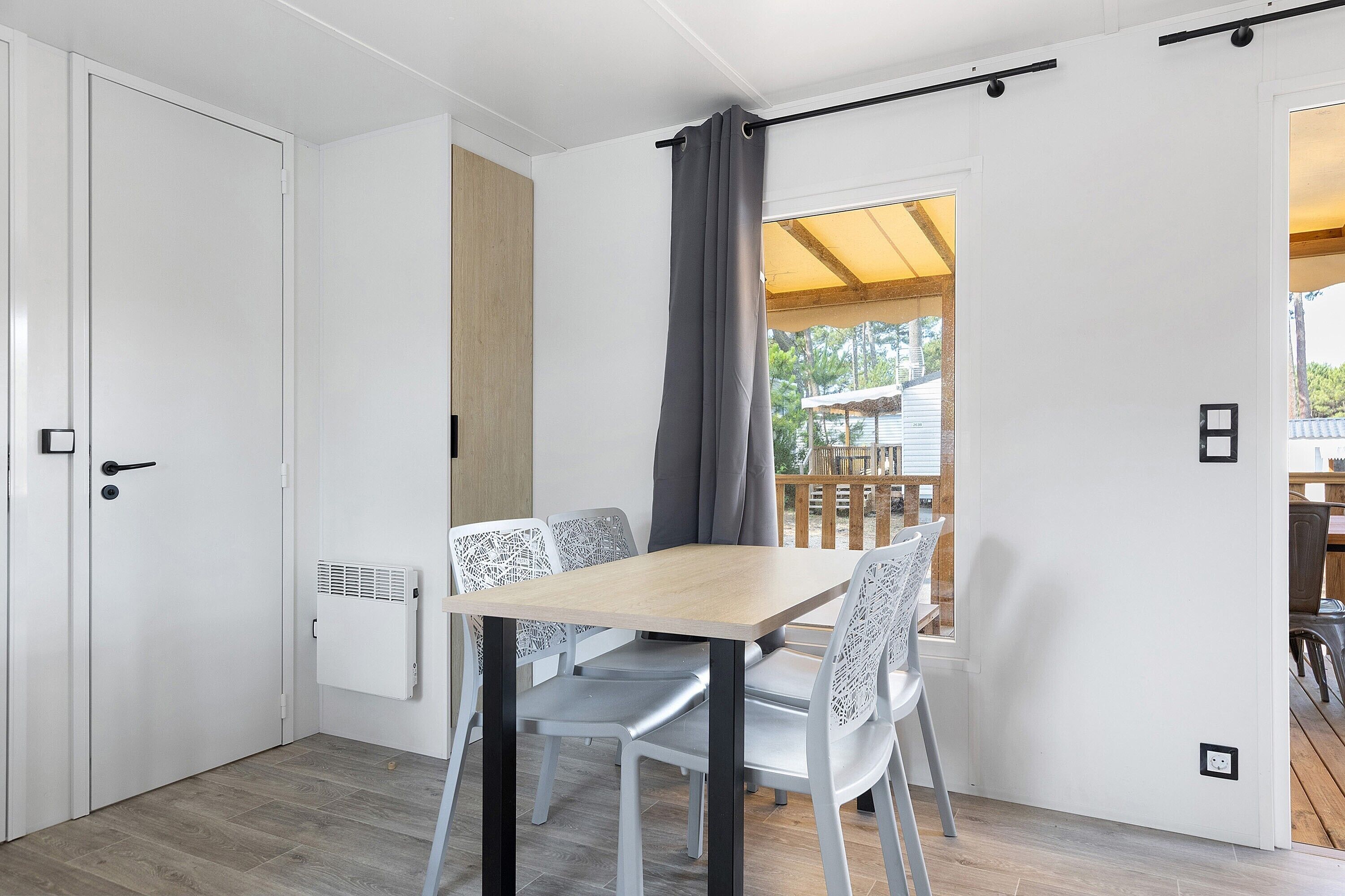 A room with a wooden table and chairs, a radiator, a sliding door, and a view of an outdoor deck.