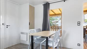 A room with a wooden table and chairs, a radiator, a sliding door, and a view of an outdoor deck.