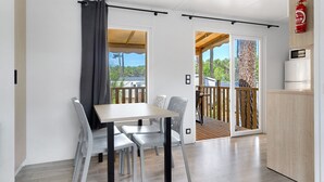 Une cuisine moderne équipée d’un four à micro-ondes, d’un meuble en bois et d’une porte-fenêtre coulissante donnant sur un balcon.