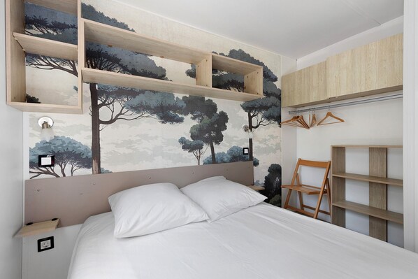 A bedroom with a bed, a headboard, a wall-mounted shelf, and a wardrobe.