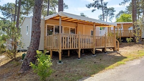 Une cabane en bois avec un porche, entourée d’arbres.