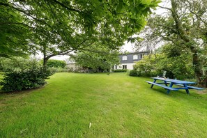 Une cour arrière verdoyante avec une table de pique-nique et une maison en arrière-plan.