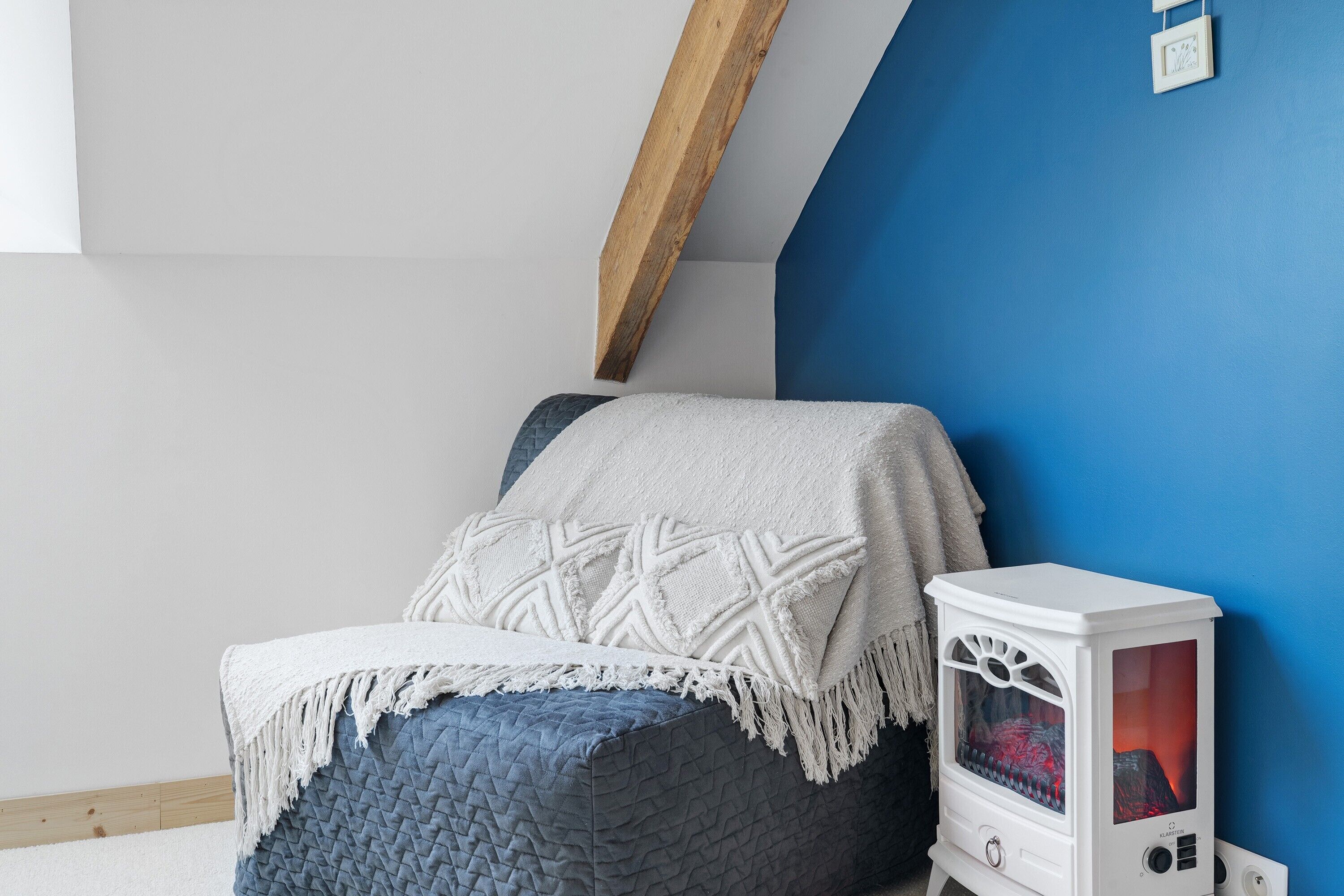 Ein Zimmer mit einem Bett, einem weißen Heizgerät und einer blauen Wand.
