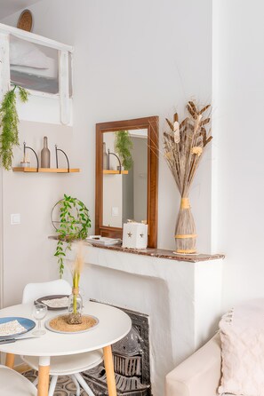 Een kamer met een witte tafel, een spiegel en planken met planten en decoratieve objecten.
