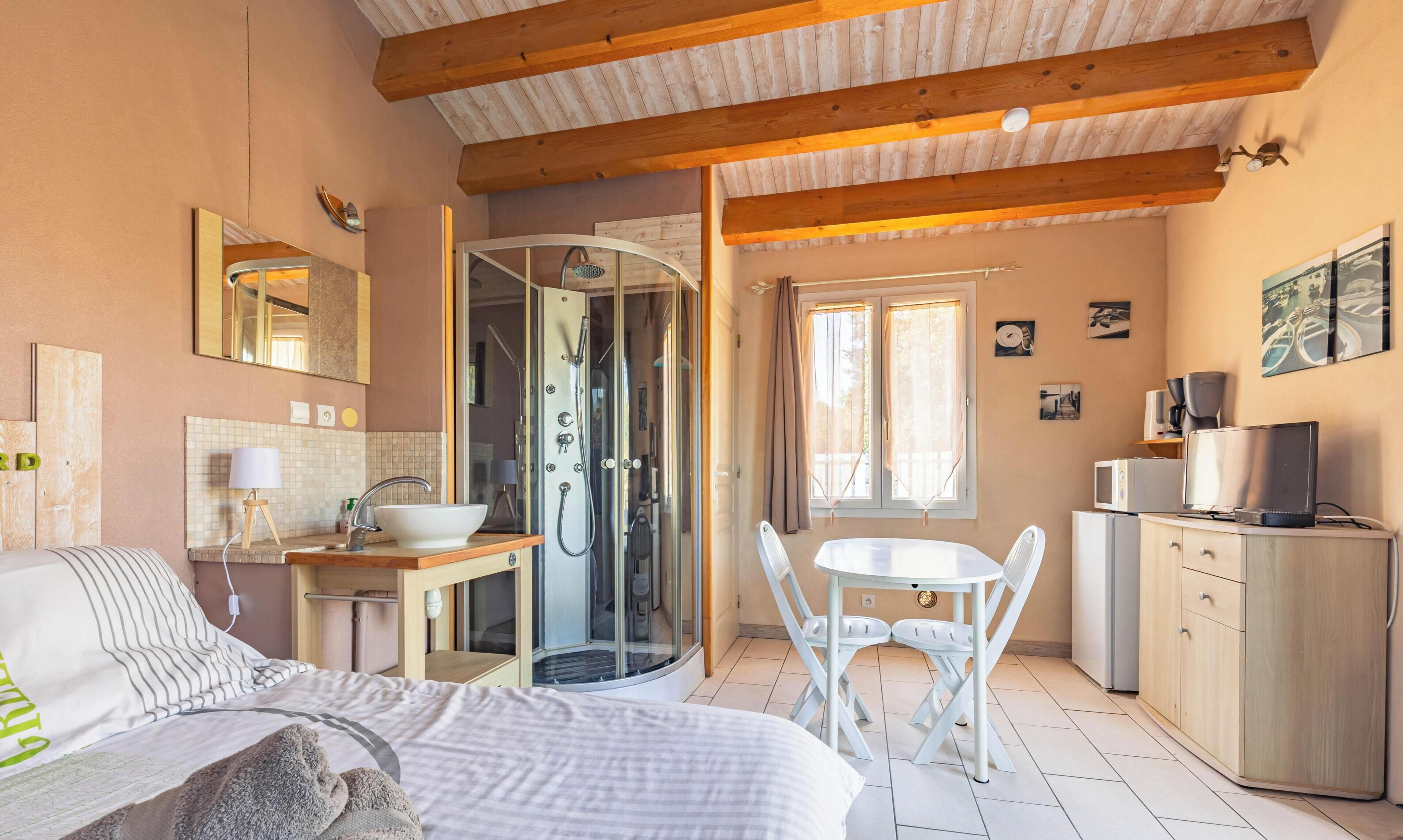 Ein Schlafzimmer mit Bett, Nachttisch und einem Badezimmer mit Dusche und Waschbecken.
