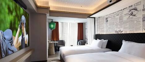 Habitación de hotel con dos camas, televisor, zona de comedor y un amplio ventanal.