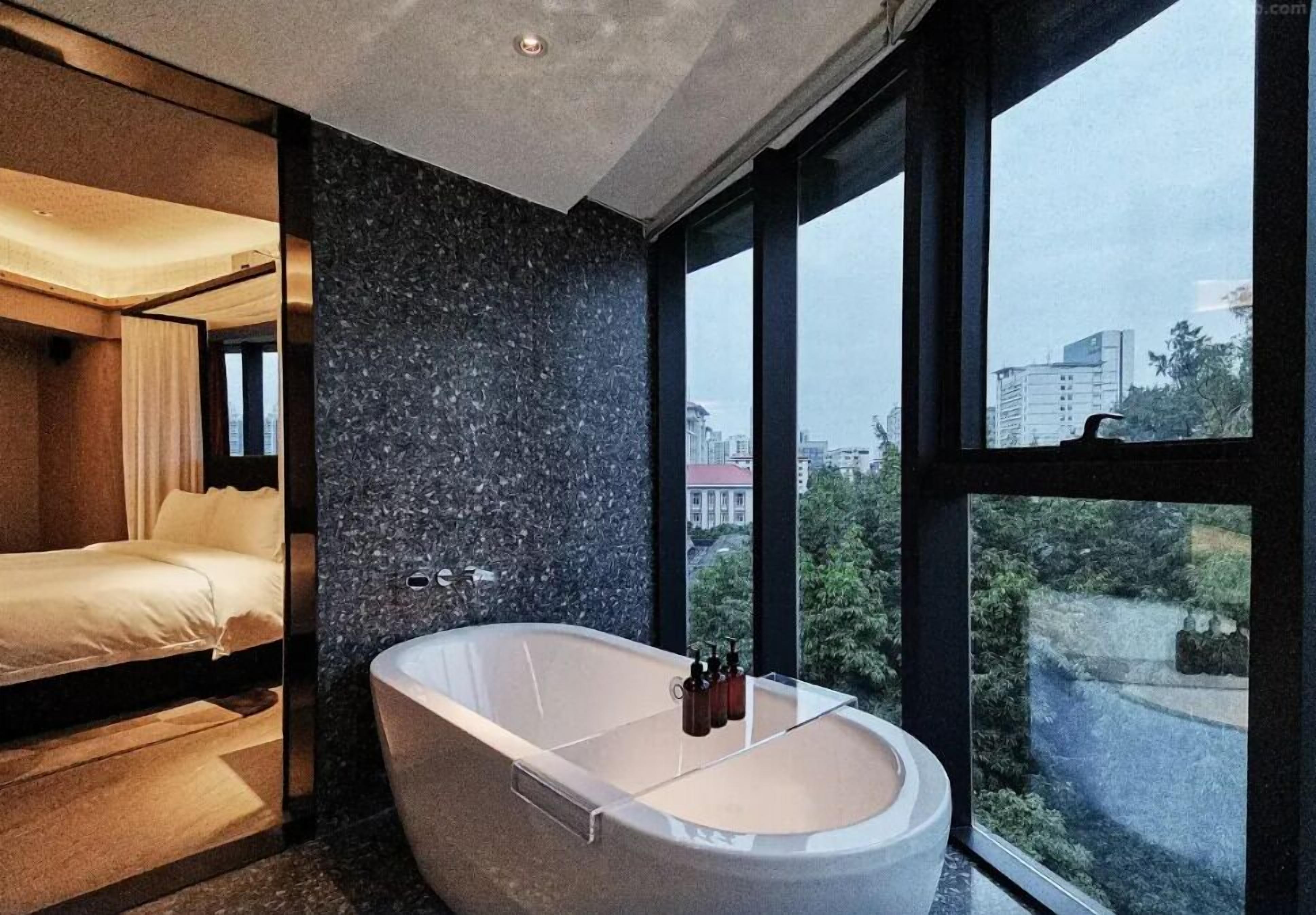 Un baño moderno con una bañera independiente, un ventanal y vista a la ciudad.