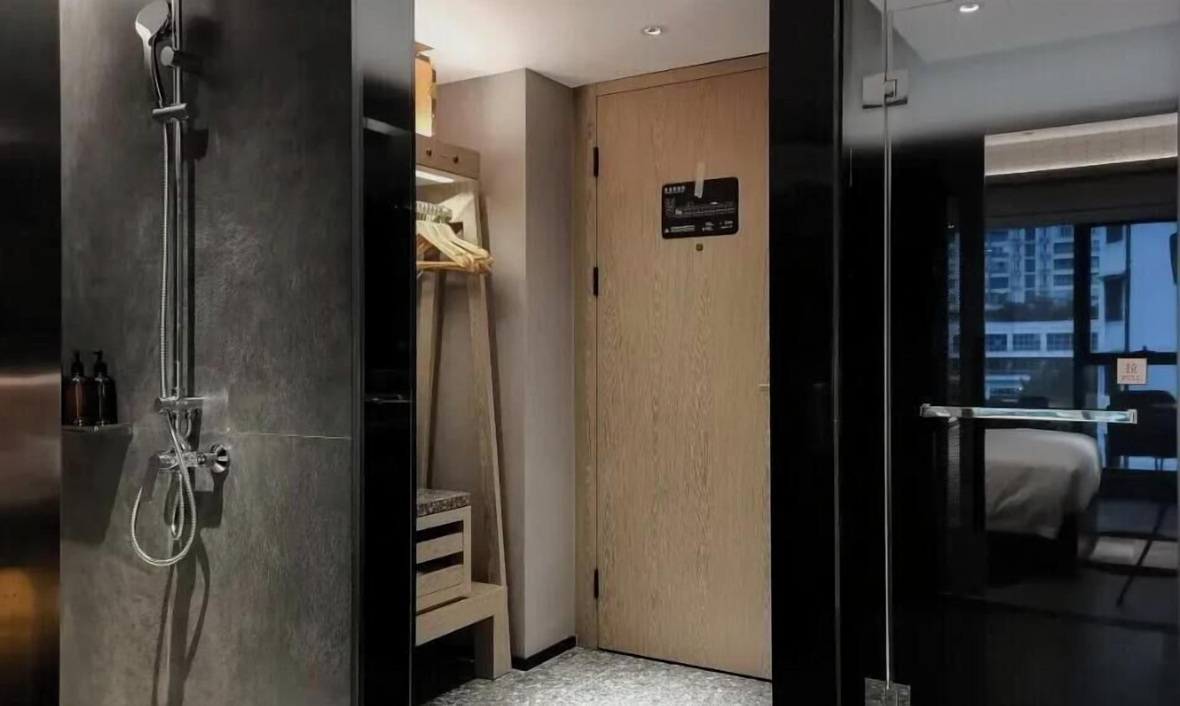 A hotel room with a shower, a wooden wardrobe, and a bed.
