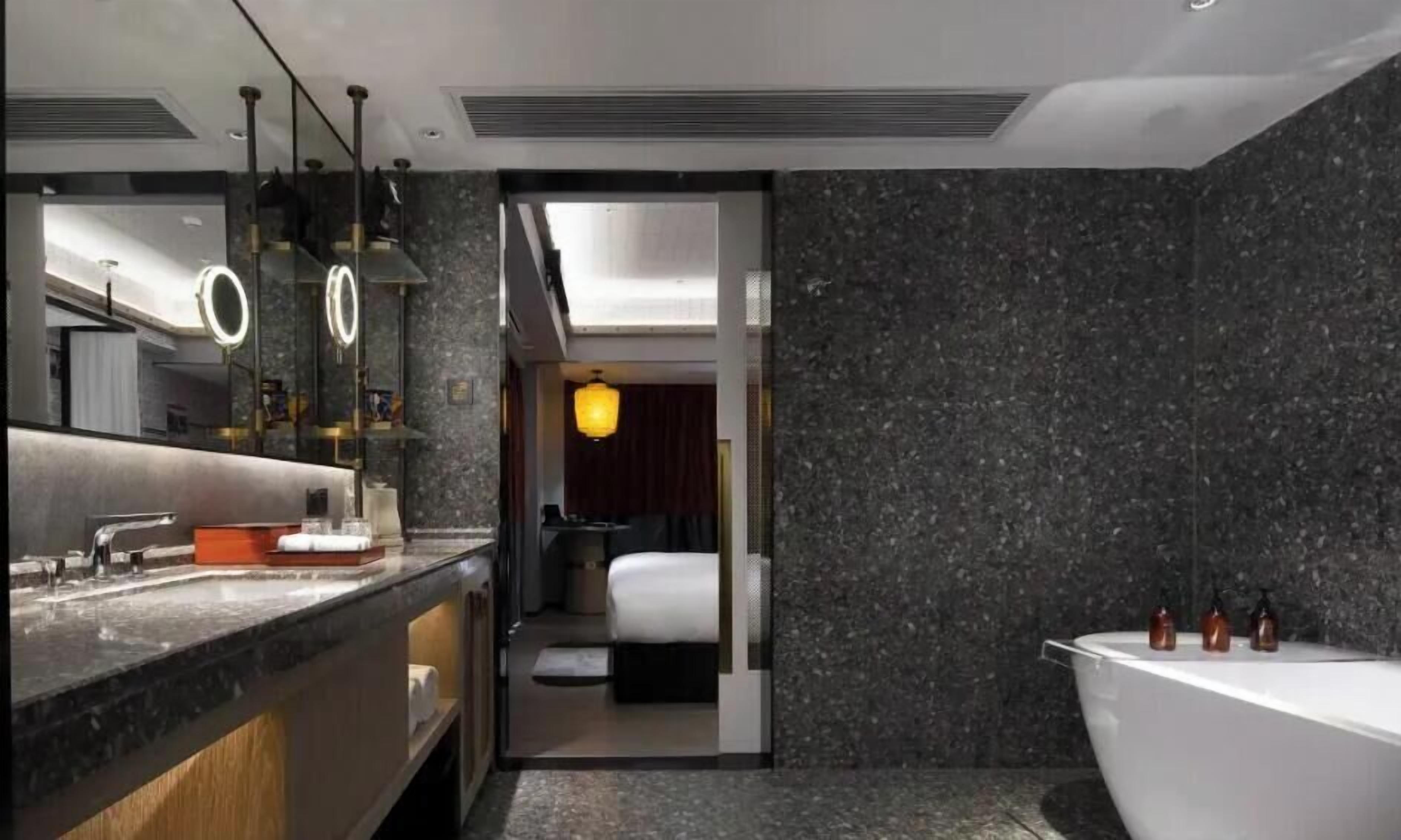 A modern bathroom with a large mirror, a bathtub, and a shower area.