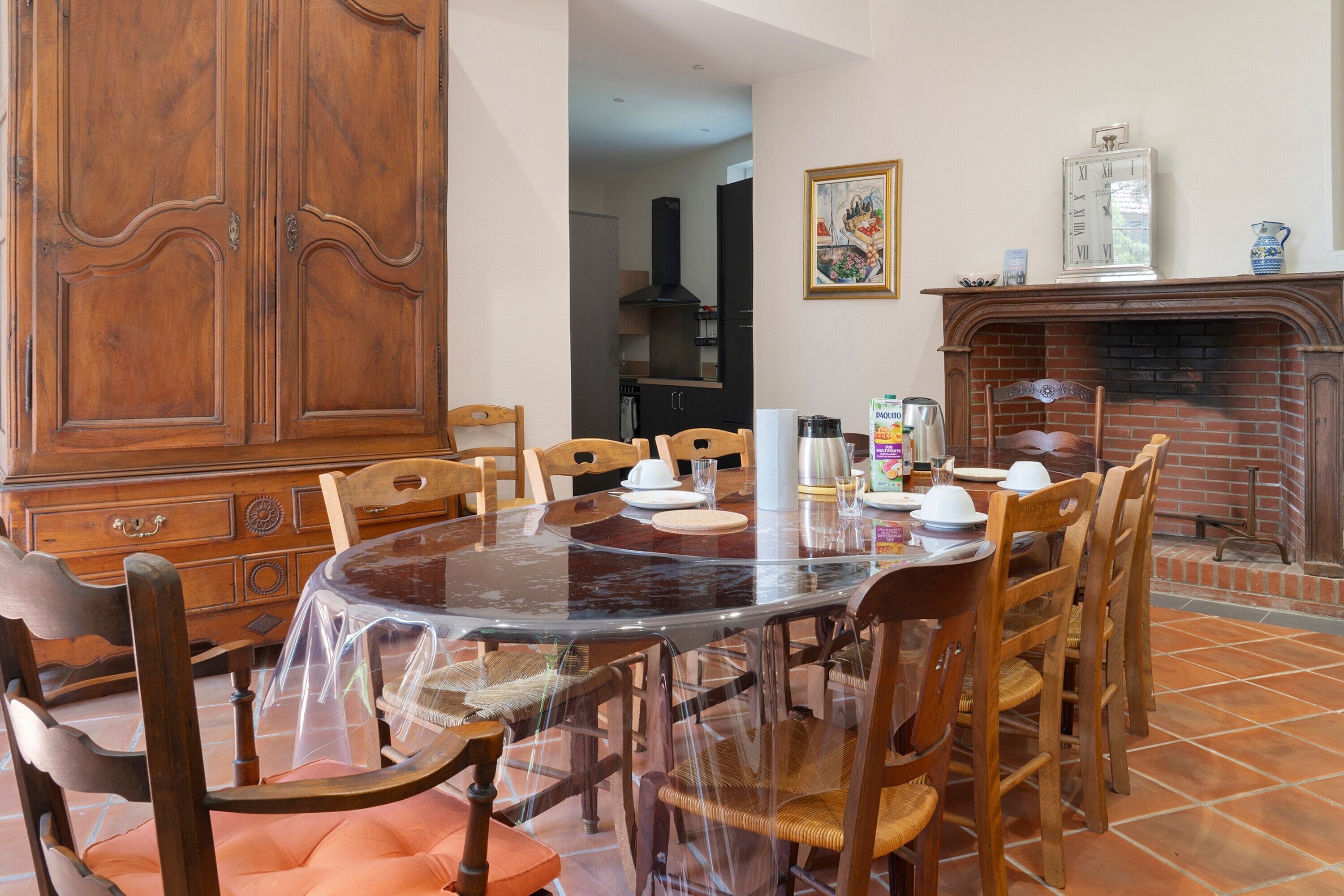 Un coin repas avec une table ronde, des chaises, un buffet en bois et une cheminée.