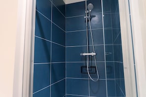 Une salle de bain avec des carreaux bleus, une pomme de douche et un pommeau de douche amovible.