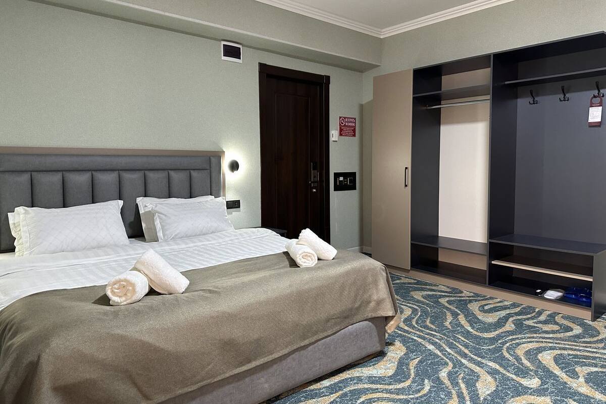 A hotel room with a bed, a wardrobe, and a bathroom.